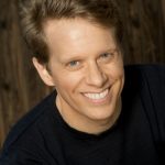 Headshot of David with a smile in a navy blue sweater