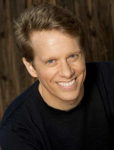 Headshot of David with a smile in a navy blue sweater